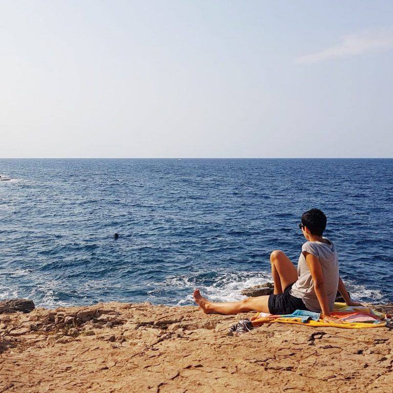 Coach aus Fürth sitzt auf einer Felskante mit Blick auf das Meer – Bild für Ruhe, Weitblick und persönliche Entwicklung.